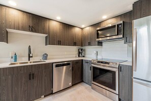 A modern kitchen with wood-paneled cabinets, stainless steel appliances, and a built-in microwave.