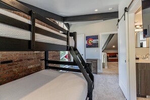 A bunk bed with a metal frame and a brick wall backdrop.