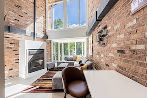 A modern living space with a fireplace, seating area, and large windows.