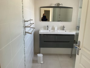 A bathroom with a white sink, dark vanity, and a mirror above the sink.