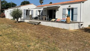 Une maison moderne dotée d’un patio, d’un petit jardin et surplombant un ciel bleu dégagé.