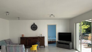 Un salon avec un canapé, un fauteuil jaune, une télévision et une horloge au mur.