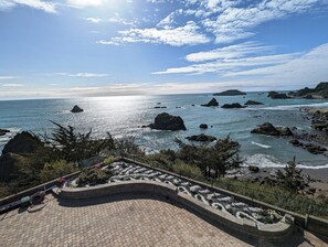 Une vue sur la côte, avec une promenade dallée, des affleurements rocheux et un ciel dégagé.