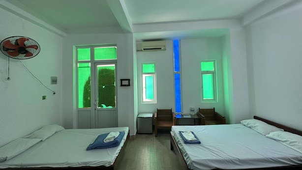 Ein Zimmer mit zwei Einzelbetten, einem Schreibtisch, einem Stuhl und einem Ventilator.