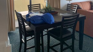 A dining area with a table, chairs, a chandelier, a potted plant, and a sofa. - Cozy oceanfront beach condo full of light (North Myrtle Beach)