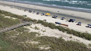 A beach with a wooden boardwalk leading to the shore, sandy beach, and ocean waves. - Cozy oceanfront beach condo full of light (North Myrtle Beach)