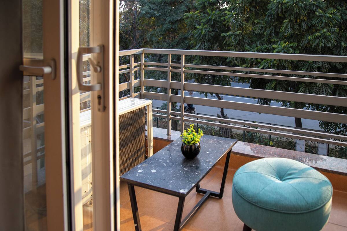Un balcón con una mesa, un banco y una planta en maceta.