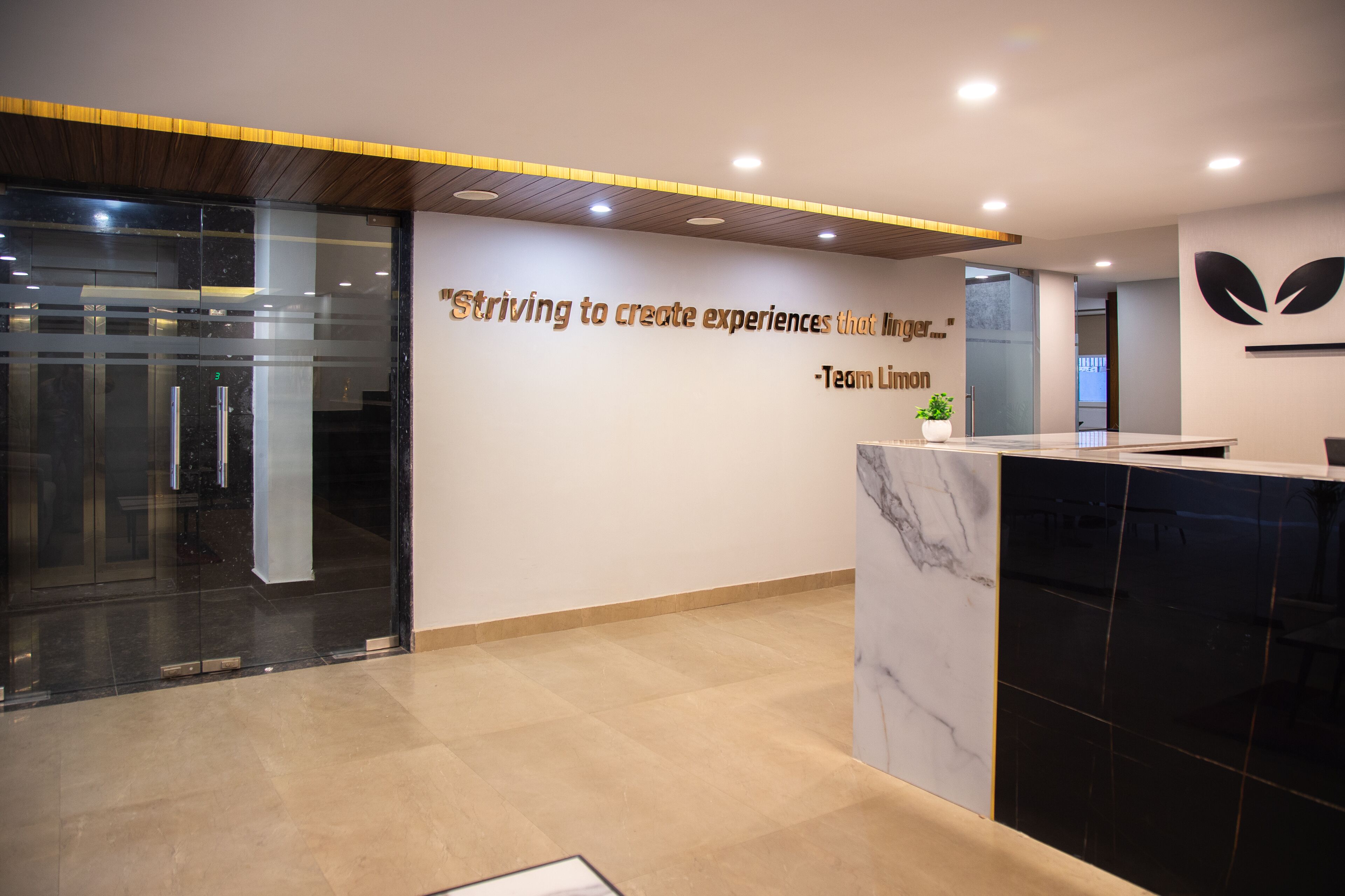 A modern reception area with a marble counter, a glass door entrance, and a motivational quote on the wall.