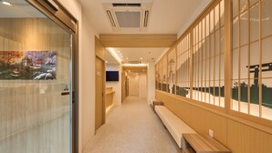 A hallway with a wooden bench, a glass door with a view of a bridge, and a wooden wall with a grid pattern. - Waka Kyoto Kawaramachi (Kyoto)