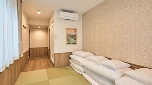 A hotel room with a wooden floor, a large bed with white bedding, an air conditioning unit, a painting on the wall, and a patterned wallpaper. - Waka Kyoto Kawaramachi (Kyoto)