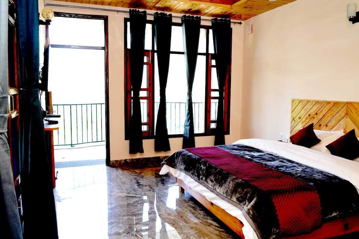 A bedroom with a bed, a wooden headboard, and a balcony with curtains.