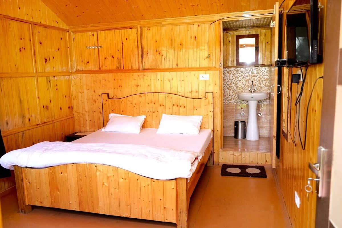 A wooden room with a bed, a sink, and a television.