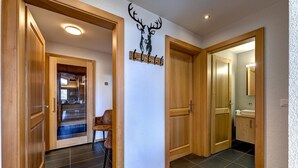 A hallway with wooden doors, a coat rack, and a wall-mounted deer head decoration. - Chalet Flocon de Neige - jacuzzi - sauna - La Tzoumaz, 4 Vallees (La Tzoumaz)