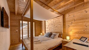 A wooden cabin bedroom with a four-poster bed, bedside lamps, and a small desk with a tablet. - Chalet Flocon de Neige - jacuzzi - sauna - La Tzoumaz, 4 Vallees (La Tzoumaz)
