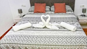 Un lit avec une couvre-lit à motifs, deux oreillers et une serviette pliée en forme de cygne.