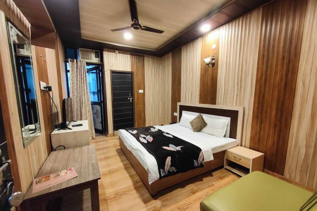 Quarto com cama, mesa de cabeceira e escrivaninha com cadeira.