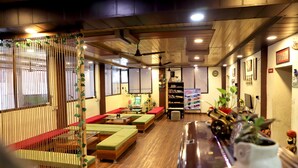 Una habitación tradicional japonesa con esteras de tatami, mesas de madera bajas y un fusuma con plantas verdes.
