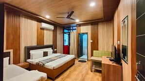 Habitación de hotel con techo de madera, cama con cabecera, escritorio con silla y televisor.
