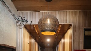 Un couloir aux murs recouverts de lambris en bois, une enseigne indiquant le troisième étage et un luminaire suspendu.