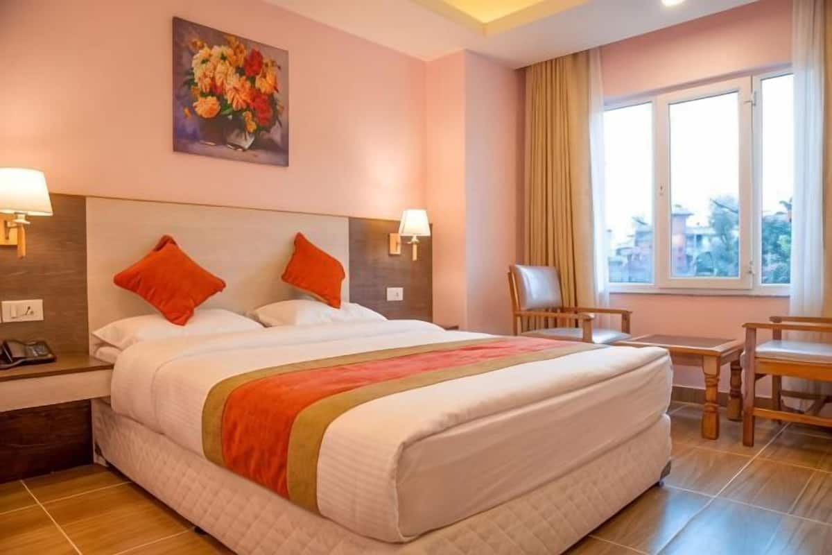 A hotel room with a large bed, two nightstands, a desk, and a chair.