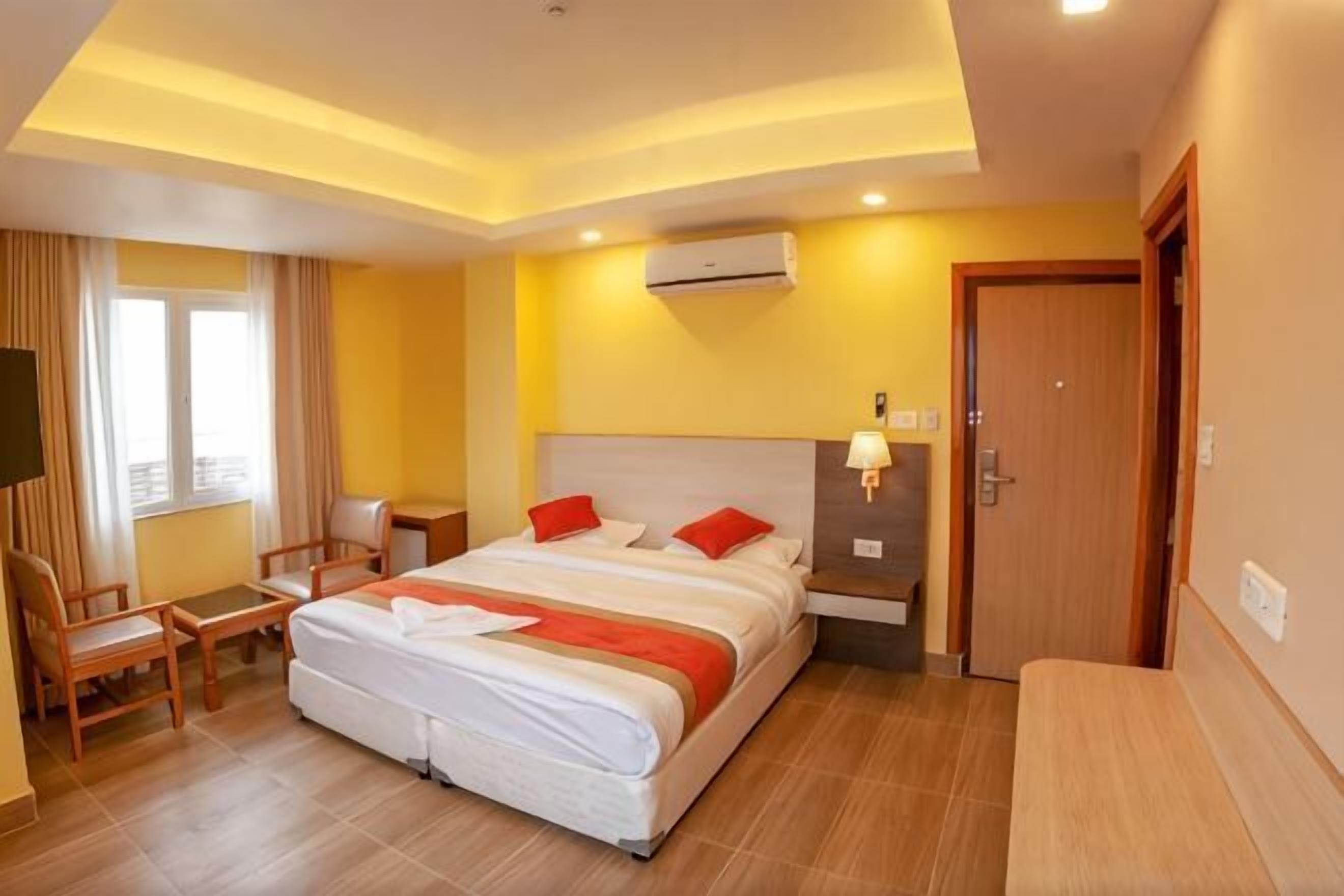 A hotel room with a large bed, bedside table, lamp, and a TV.