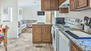 A kitchen with wooden cabinets, a microwave, stove, and a dining area with a table and chairs. - Blue Mountainview welcomes long stays (Mariposa)