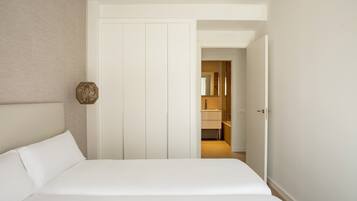A bedroom with a large bed, a wardrobe, and a bathroom visible through an open door.