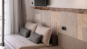 Ein modernes Schlafzimmer mit Schlafsofa, an der Wand montiertem Fernseher und Holzaufhängern.