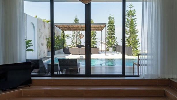 Un interior moderno con un amplio ventanal corredera que da a una zona de piscina exterior.