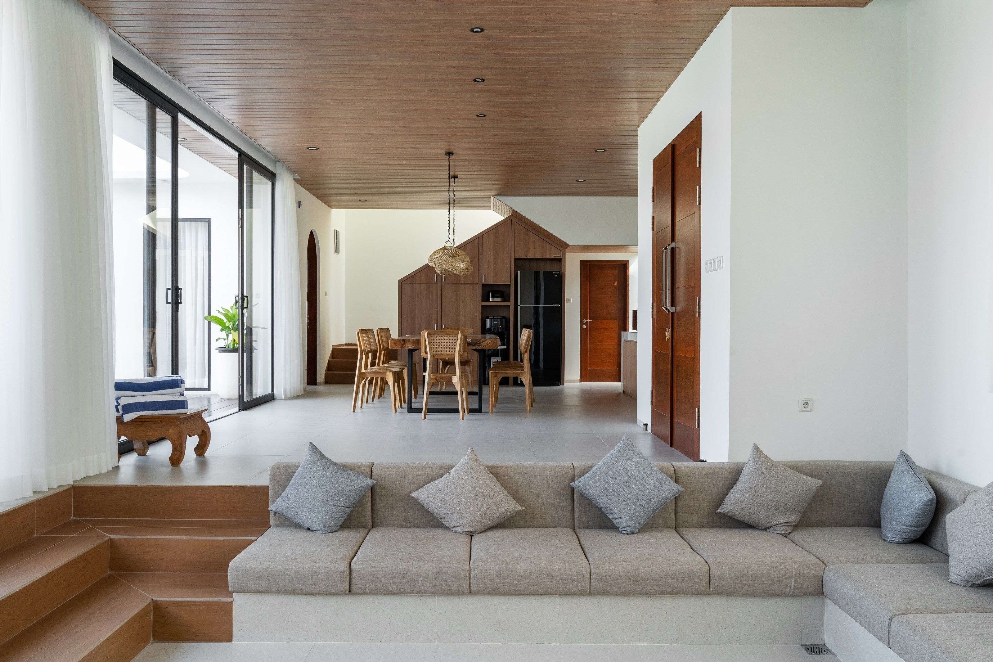 Una sala de estar moderna con sofá, zona de comedor y escalera.