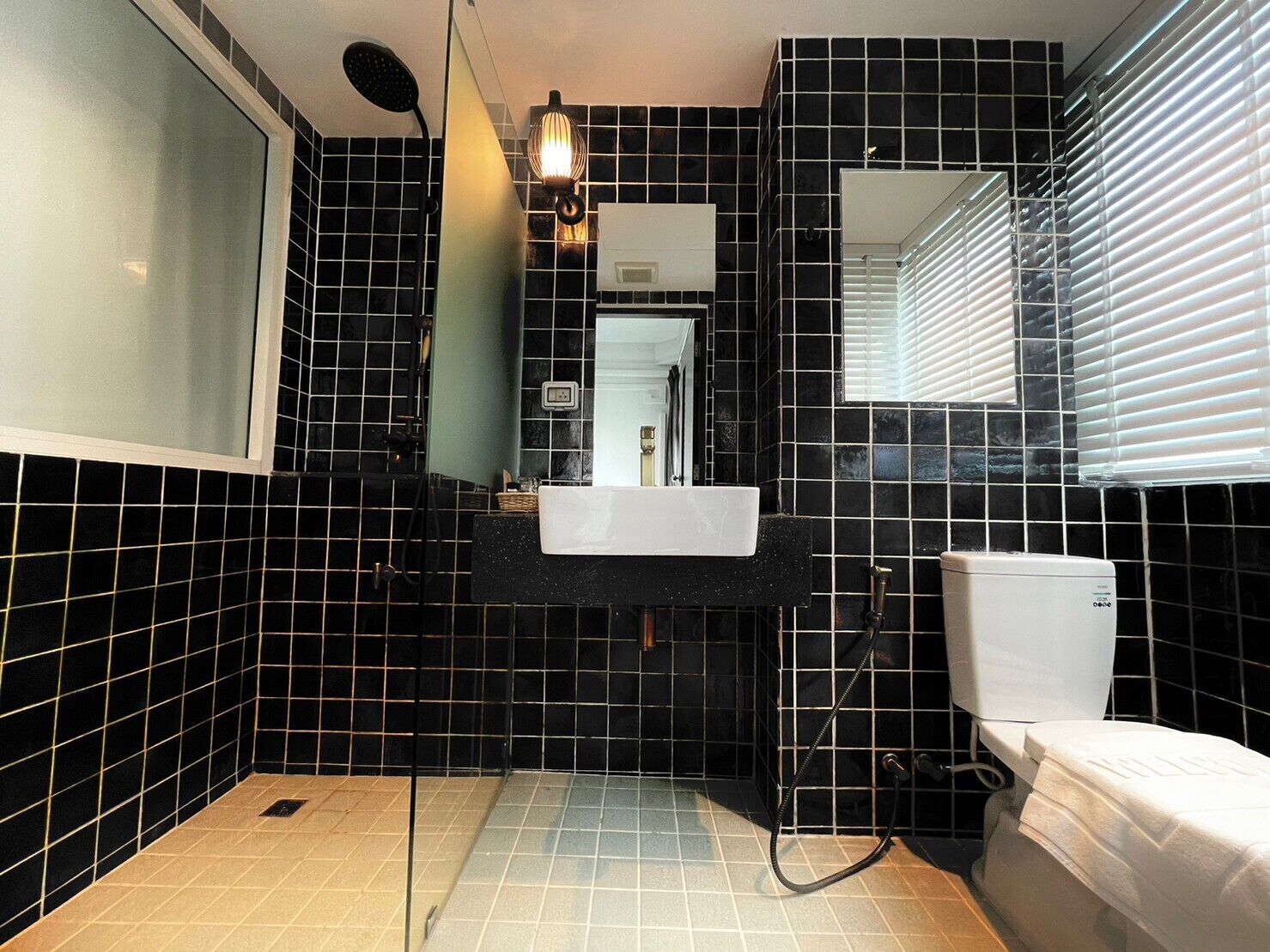 A bathroom with black tiled walls, a white sink, and a toilet.