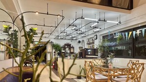 Ein modernes Interieur mit einer zentralen Bar, Korbmöbeln und hängenden Pflanzen.