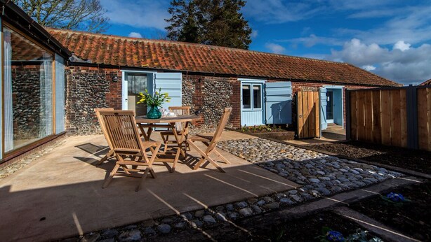 A patio with a table and chairs, a stone wall, and a wooden fence.
