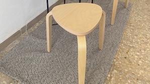 A small, round, black table with a wooden bowl and a potted plant on top.