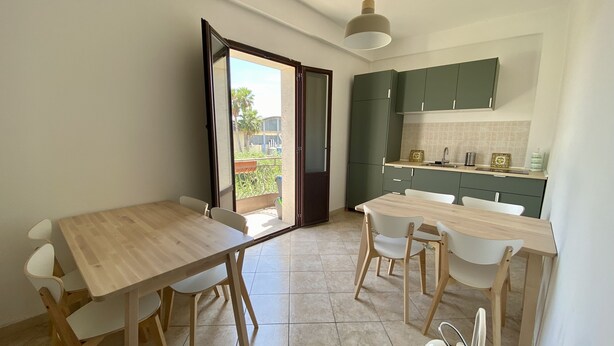 A modern kitchen with green cabinets and a dining area with a wooden table and chairs.