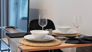 A neatly arranged dining table with a white bowl, two wine glasses, and a salt and pepper shaker. - Spacious Studio in Oasis 714 (Abu Dhabi)