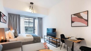 A modern hotel room with a bed, a sofa, a dining table with chairs, a TV, and artwork on the walls. - Spacious Studio in Oasis 714 (Abu Dhabi)