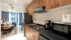 A modern kitchen with wooden cabinets, a stainless steel sink, a microwave, and a coffee maker. - Spacious Studio in Oasis 714 (Abu Dhabi)