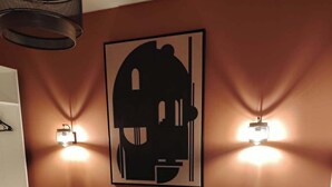 Et hotelværelse med en seng, to sengeborde med lamper, et kunstværk på væggen og trægulv.