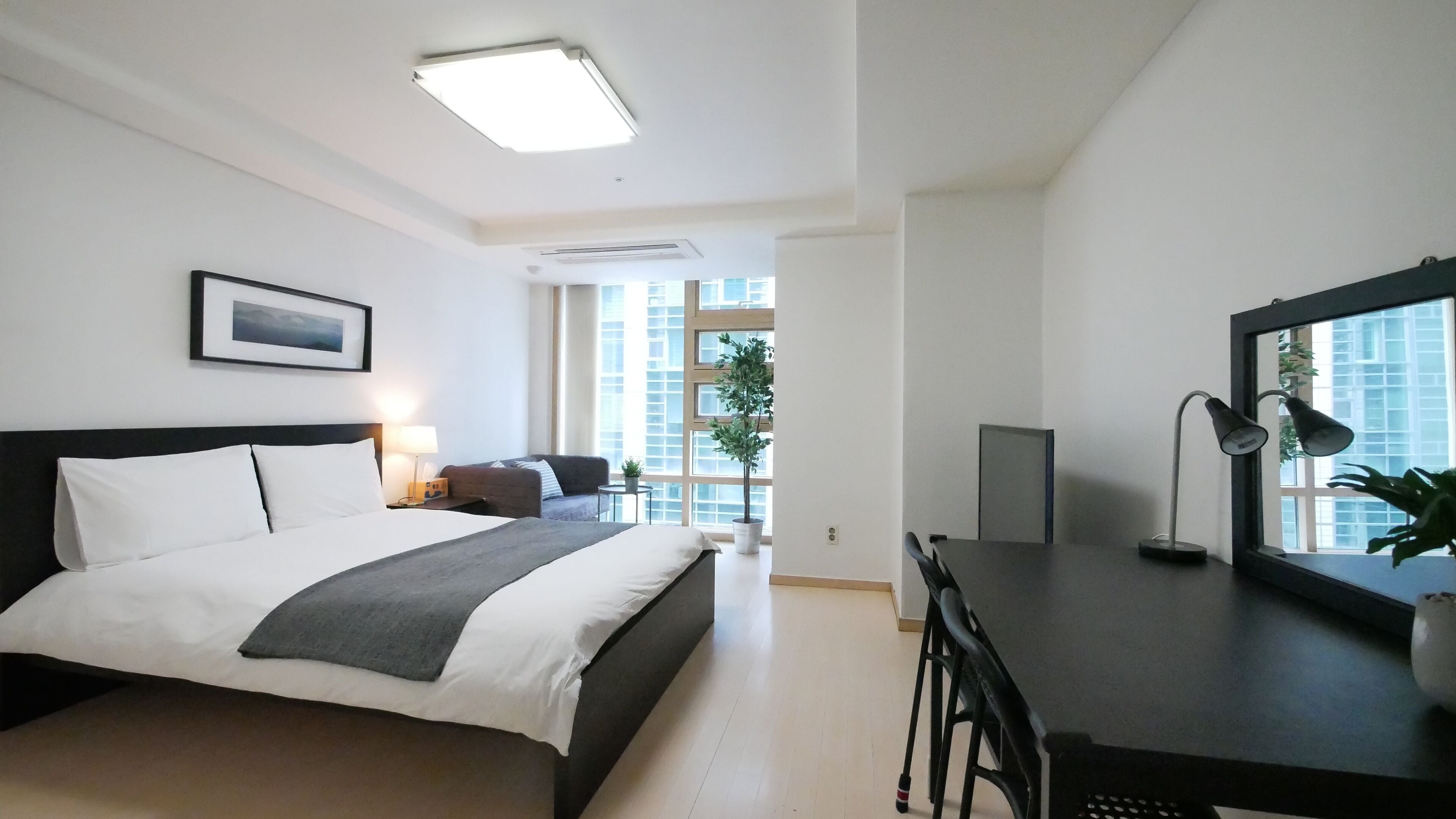 Une chambre d’hôtel moderne, dotée d’un grand lit, d’un bureau et d’une fenêtre donnant sur la ville.