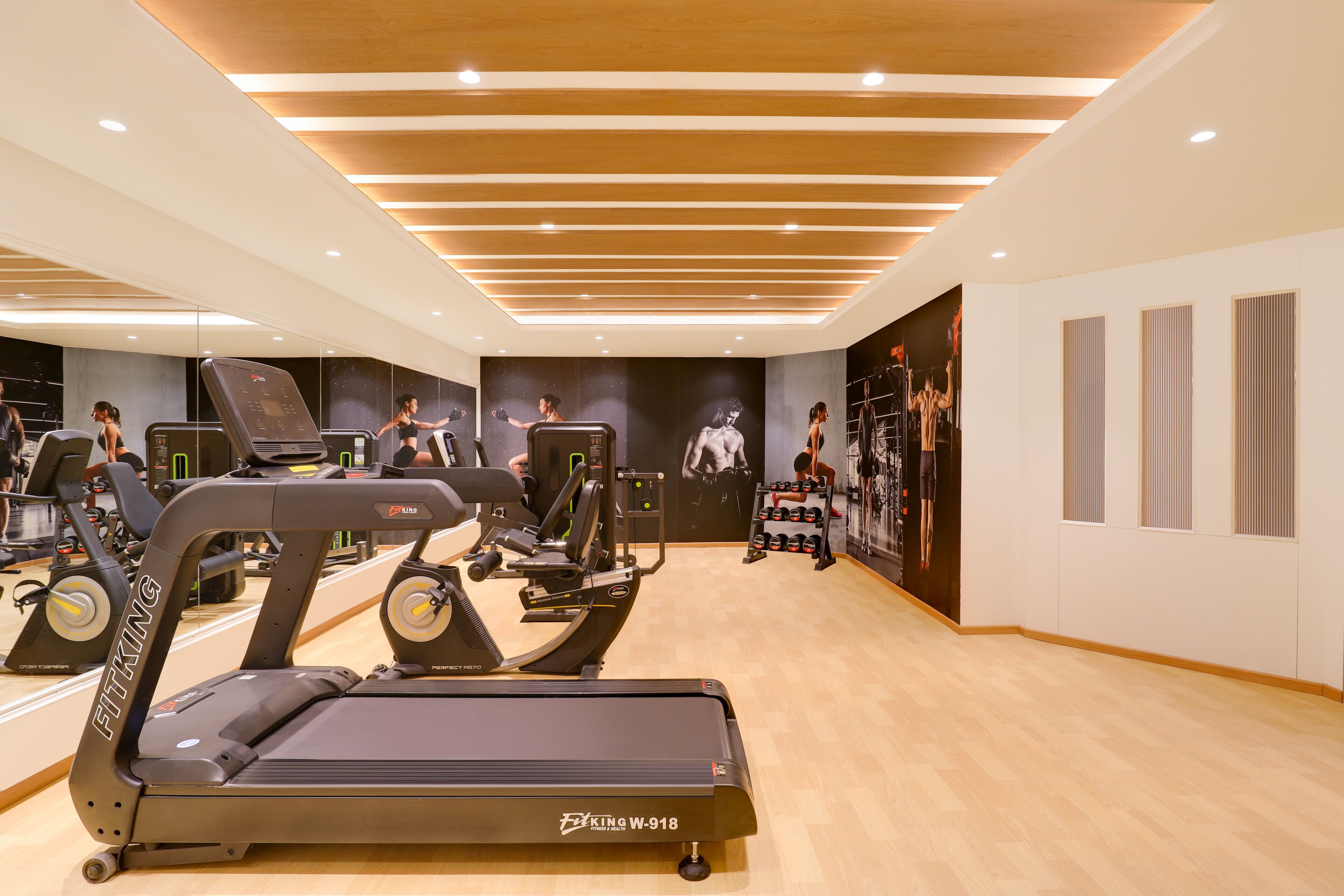Un gimnasio con cintas de correr, máquinas de pesas y un espejo grande.