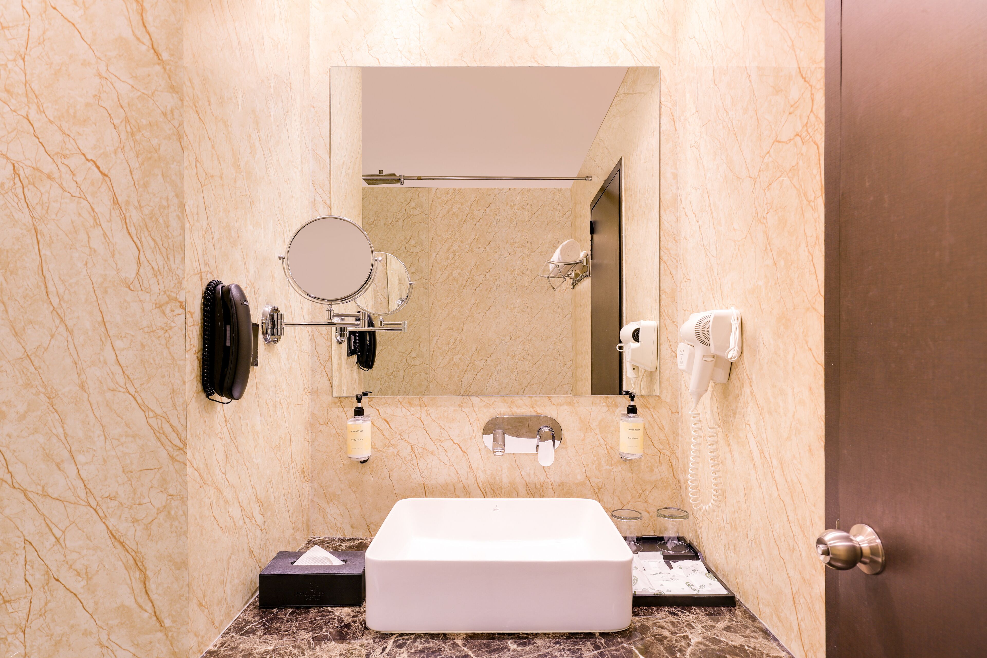 Une salle de bain avec un lavabo en marbre, un miroir, un sèche-cheveux et un porte-serviettes.