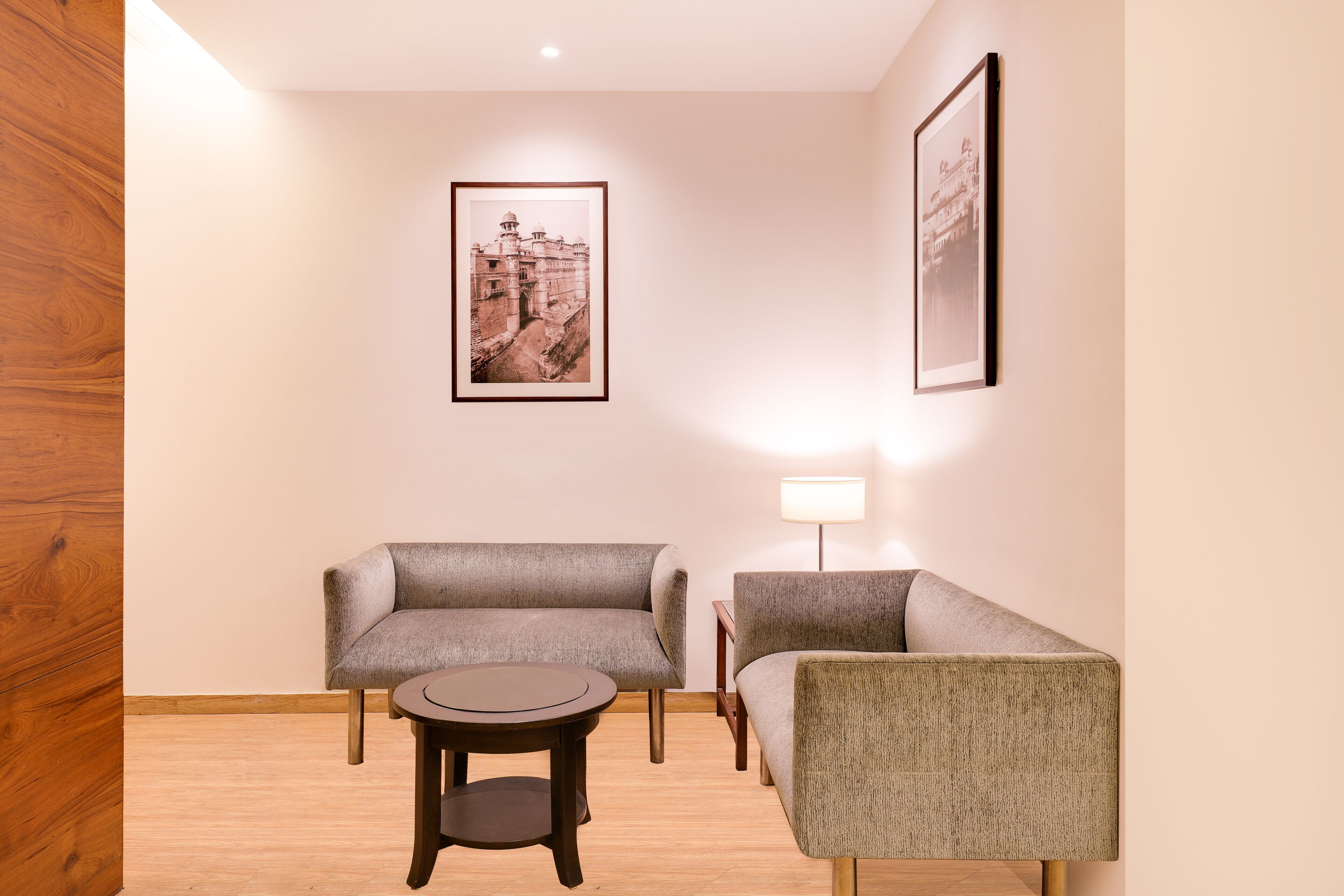 A room with two grey sofas, a small round table, and a framed picture on the wall.