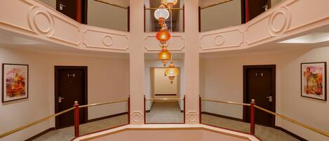 A multi-level interior with a central staircase, doors numbered 209 and 210, and hanging decorative lanterns.