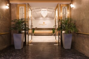 A hotel reception area with a modern design, featuring a reception desk, a chandelier, and potted plants. - Lemon Tree Hotel Bhopal (Bhopal)