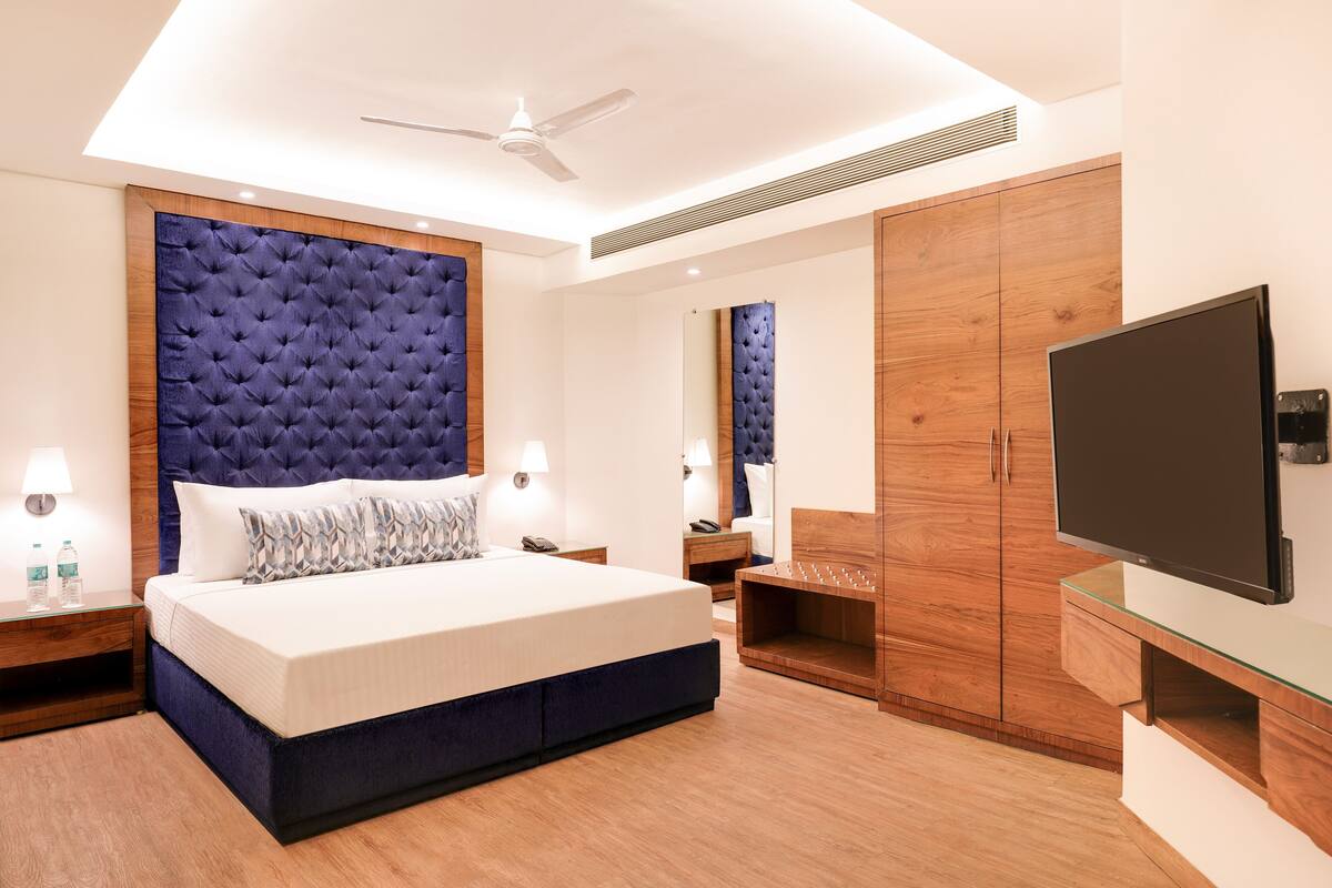Una habitación de hotel moderna con una cama grande, un armario de madera y un televisor de pantalla plana.