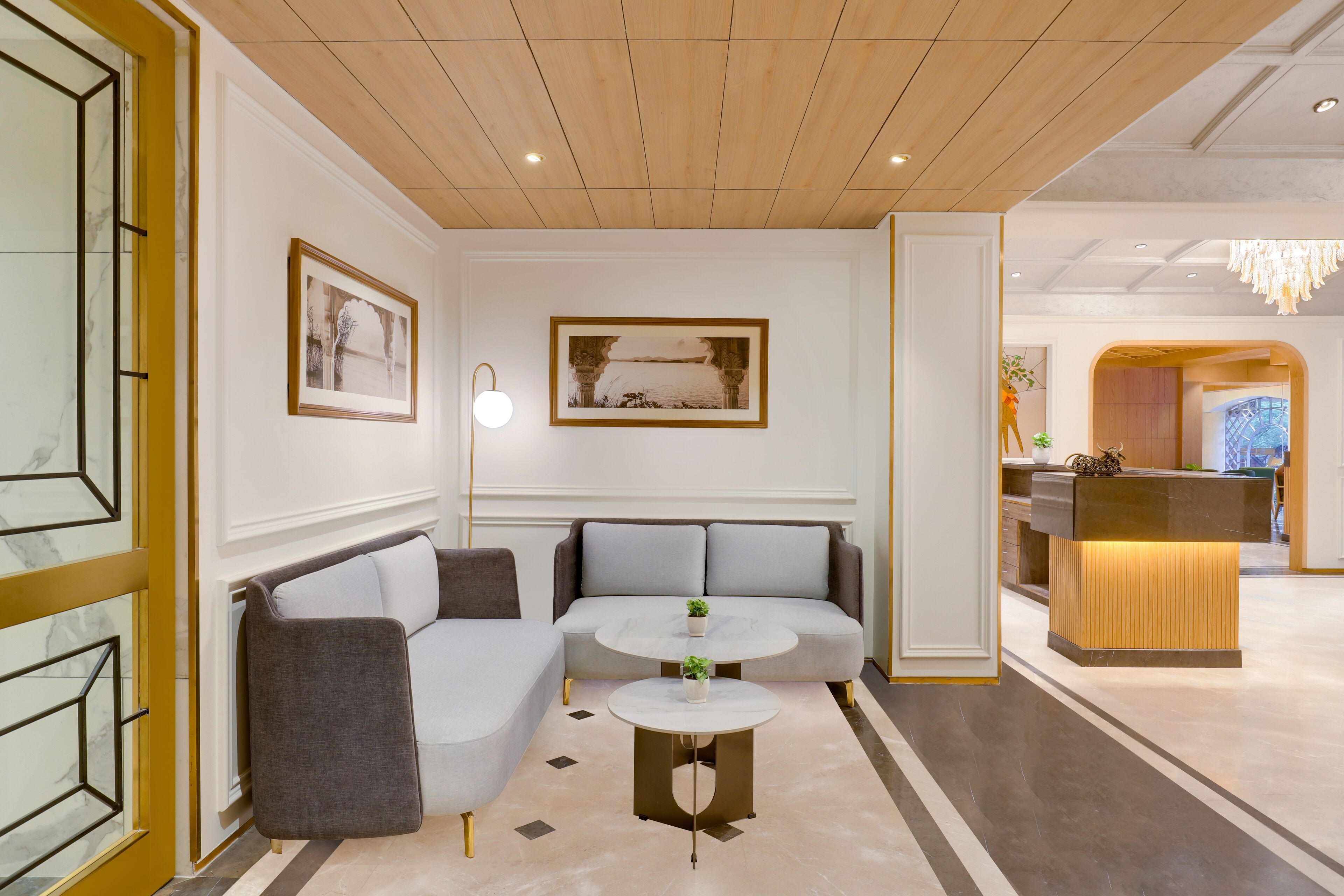Eine moderne Lobby mit einer Couch, zwei runden Tischen und einem Empfangsbereich.