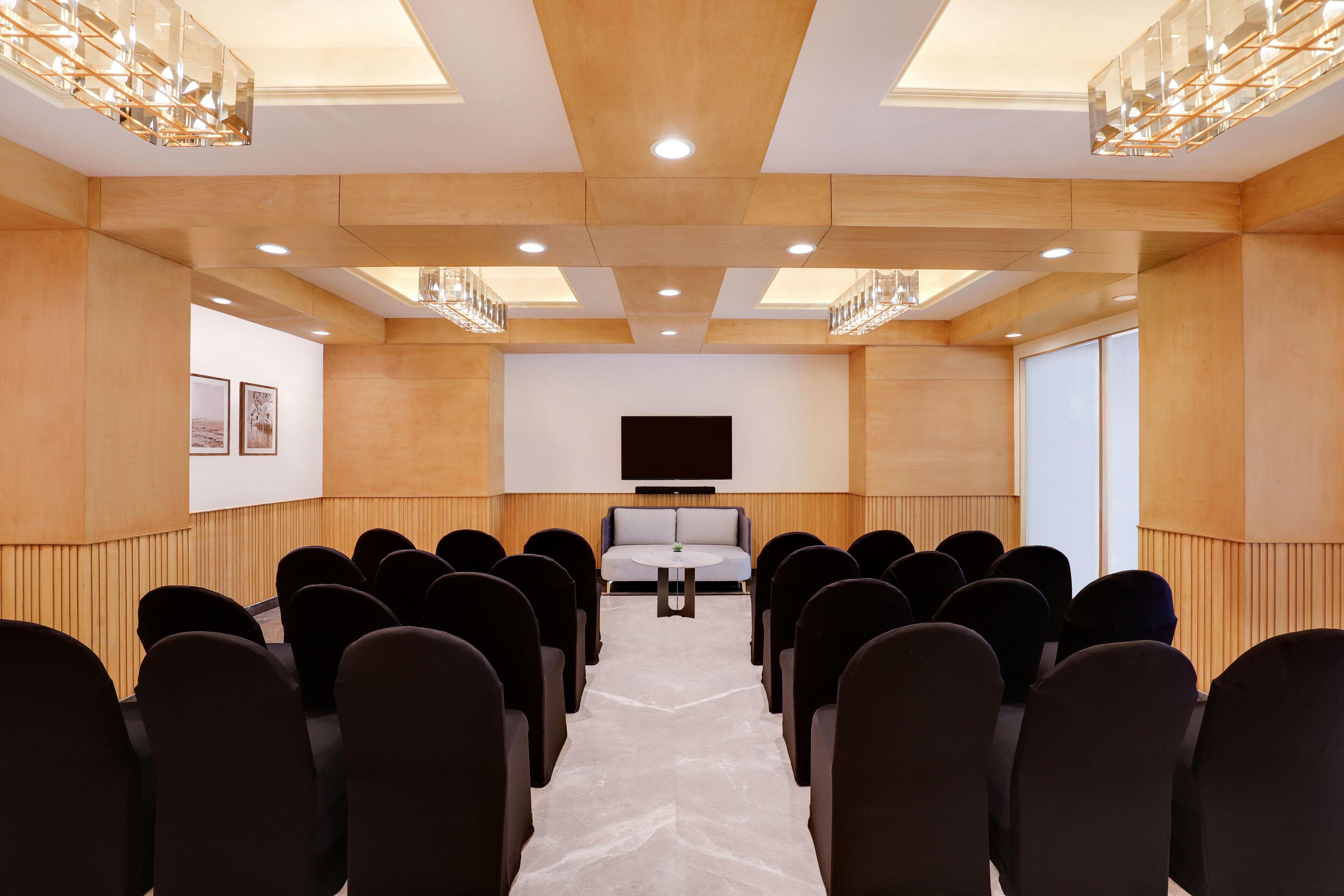 A conference room with rows of chairs, a central table, and a large screen.