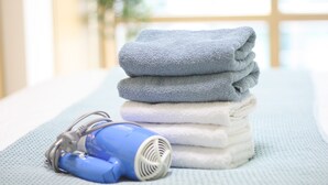 Une pile de serviettes pliées et un sèche-cheveux bleu sur une surface texturée.