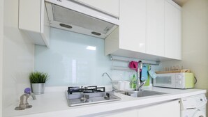 Une cuisine moderne avec des meubles blancs, une cuisinière à gaz, un four à micro-ondes et un lave-linge.